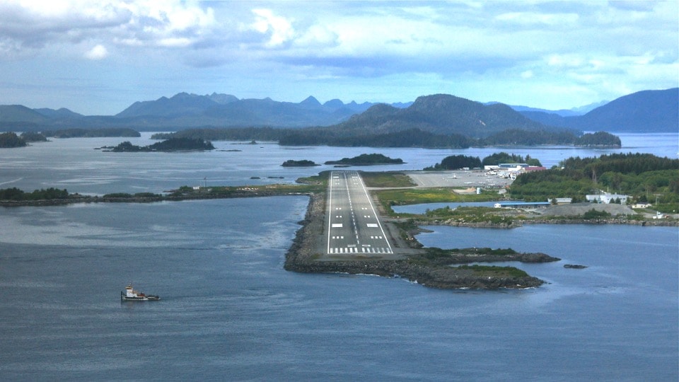 Aerial view of Sitka Airport runway on a coastal peninsula surrounded by water and mountains