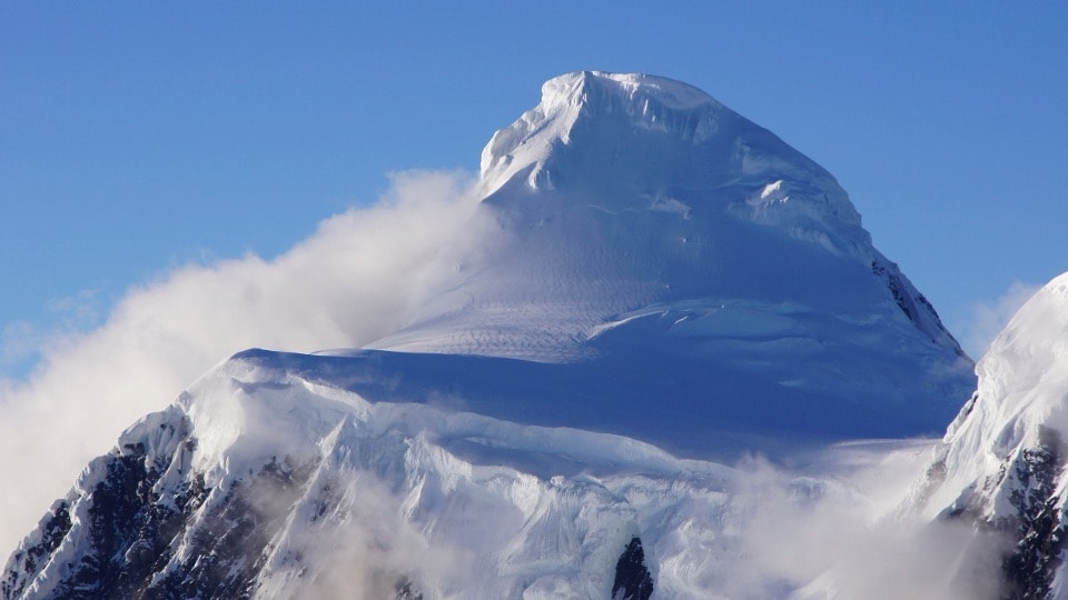 Snow-capped Alaska mountain peak rising above the clouds