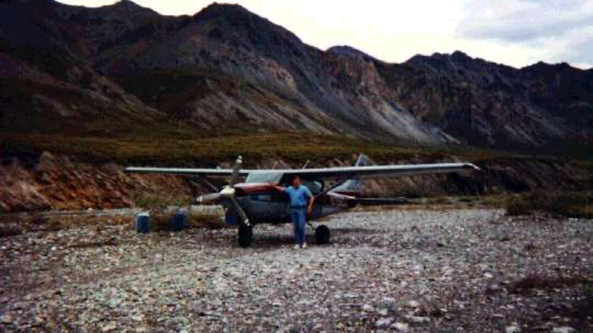 Pilot standing next to a Cessna on a remote Alaska gravel airstrip in the Brooks Range