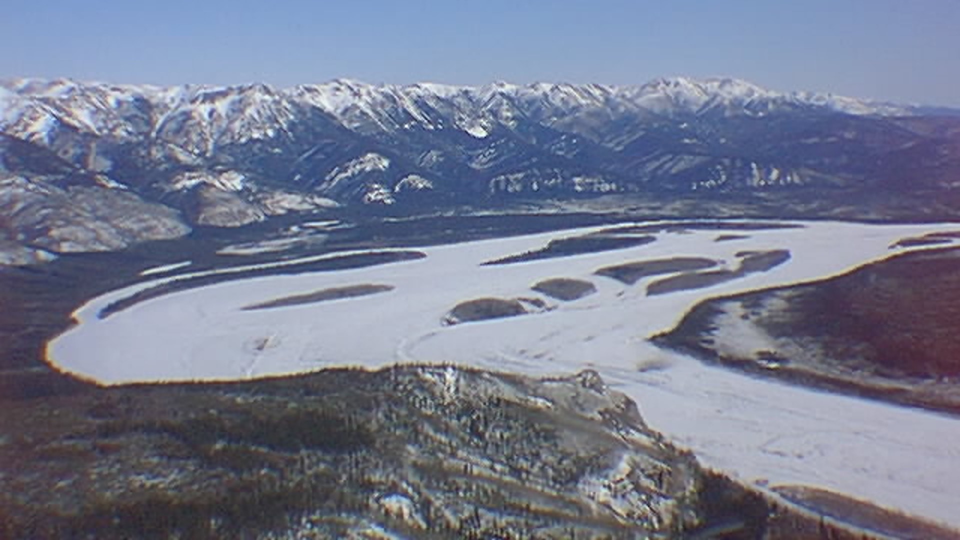 Aerial view of the frozen Yukon River winding through snow-covered Alaska mountains