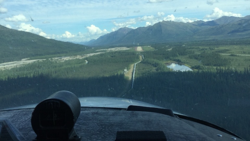 Cockpit view on approach to Coldfoot airstrip through a forested Alaska valley