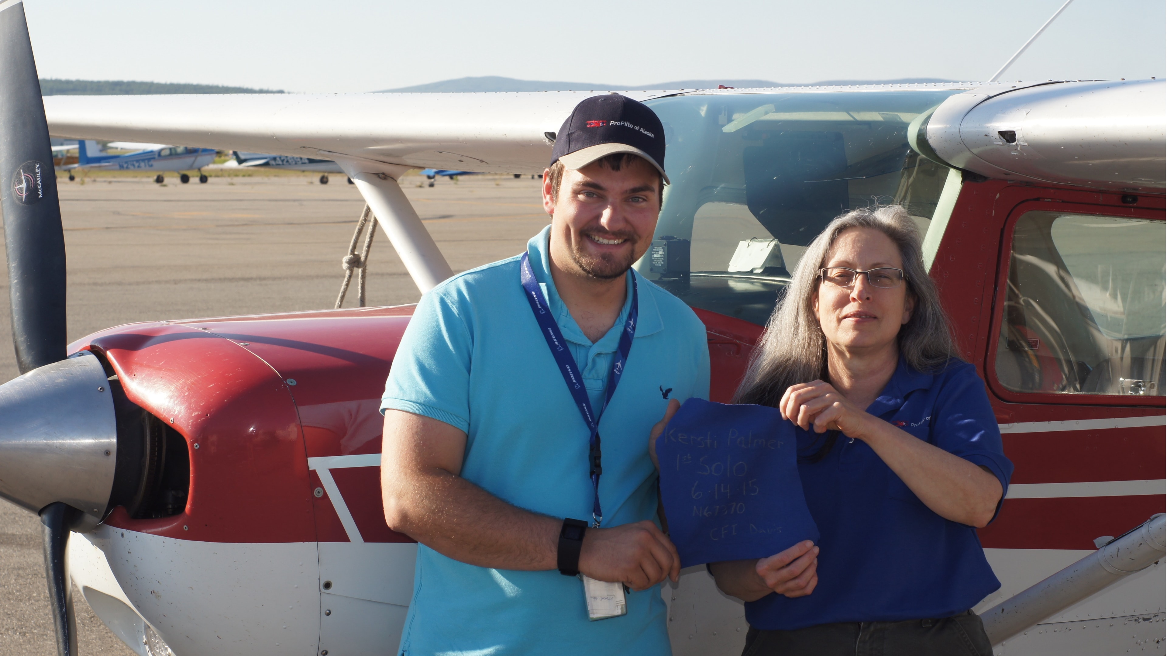 Kersti solo flight celebration — student and instructor holding shirt with solo details in front of ProFlite aircraft