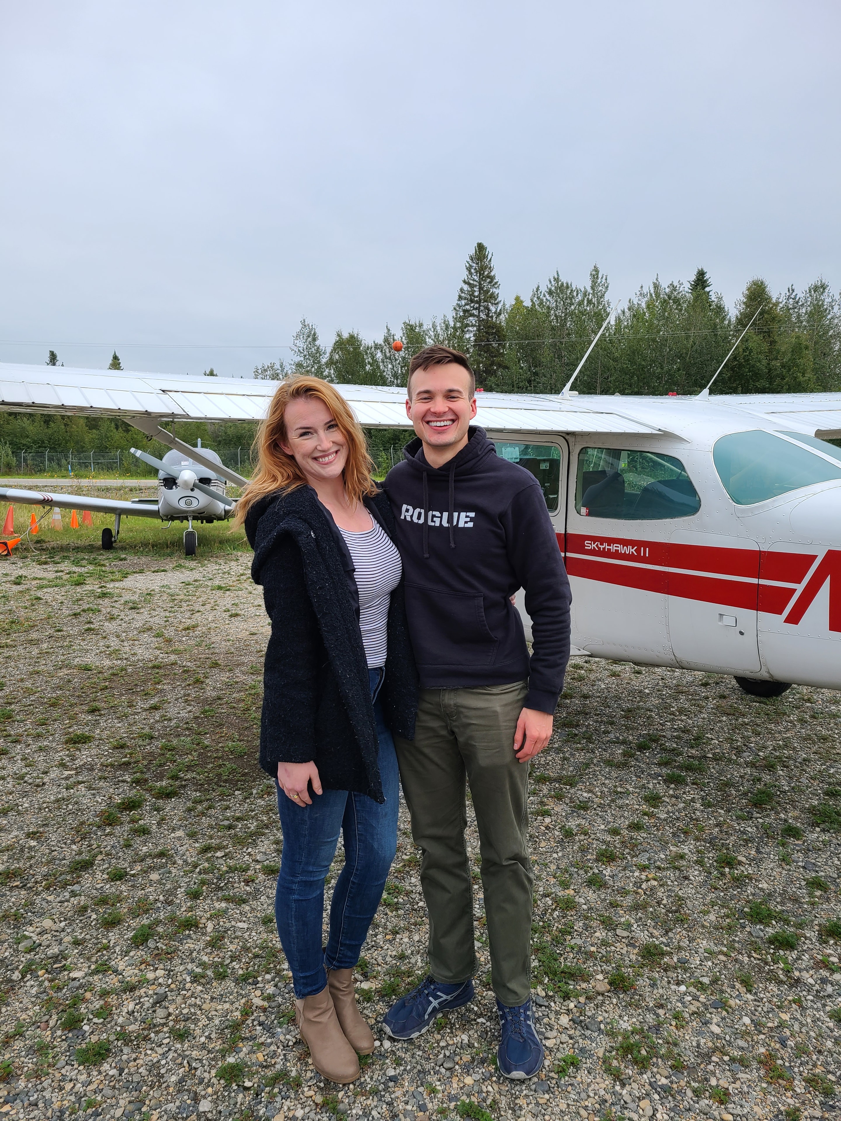 Two students smiling in front of a ProFlite Cessna Skyhawk II on the ramp